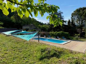 a swimming pool in a yard with chairs around it at La Cabane de l'Orpailleur in Gravières