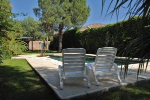 two white chairs sitting next to a swimming pool at Chalet San Rafael in San Rafael