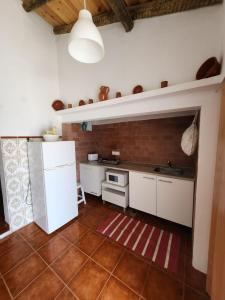 a kitchen with white appliances and a brick wall at Campinho Guest house in Campinho