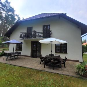 a patio with tables and umbrellas in front of a house at Willa Roztocze in Zwierzyniec