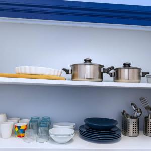 a kitchen shelf with dishes and pots and pans at Le Nid de Perrache Comfortable and Stylish Studio in Lyon