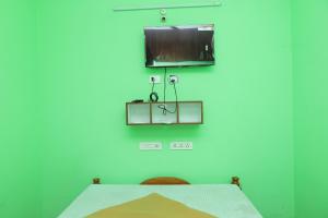 Una habitación con una mesa y un televisor en la pared. en WHITRS INN Vandalur, en Vandalūr