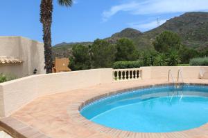 a swimming pool next to a wall and a mountain at Casa Pia in Turre