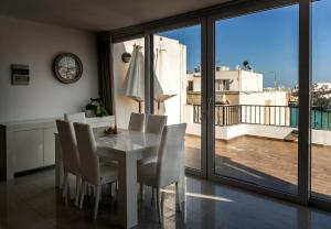 a dining room with a table and chairs and a balcony at Bellavista Bayview Penthouse Terrace in Marsaskala