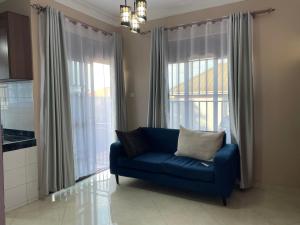 a blue couch in a living room with windows at Cozy Hideaway Kungu in Kampala
