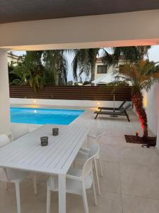 a white table and chairs in front of a pool at Katikies Grand - Superior Villa Adults Only in Pissouri