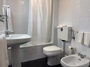 a white bathroom with a toilet and a sink at Residencial Deu-La-Deu by Hotel Dom Afonso in Monção +2 photos