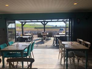 a restaurant with wooden tables and chairs and a patio at Pitlessie Rooms at Pitlessie Village Inn in Pitlessie