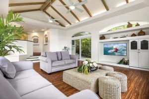 a living room with white furniture and a tv at Honu Hale in Kailua-Kona