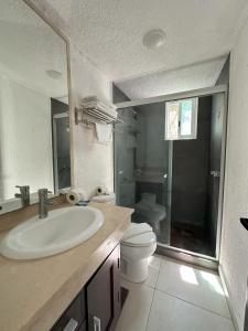 a bathroom with a sink and a toilet and a mirror at Cozy Apartment in Cancun in Cancún