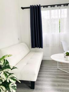 ein weißes Sofa in einem Zimmer mit Fenster in der Unterkunft The Snow Cottages in Pakha