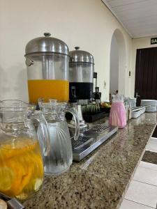 a kitchen counter with a juicer and pitchers of orange juice at Hotel Comodoro De Livramento in Santana do Livramento