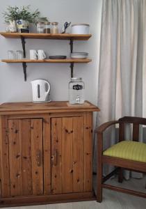 un mobiletto di legno accanto a una sedia e degli scaffali di Aan de Granaat Gastehuis a Beaufort West Altre 28 foto