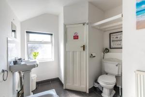 un bagno con un water, un lavandino e una finestra di Spacious 5BR House in Central Derby - Near Amenities a Derby