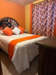 a bedroom with a bed with orange walls and a window at Rincón de Checo in Mexico City