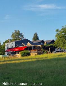 una casa con tetto rosso e campo verde di Hôtel Restaurant du Lac a Camps