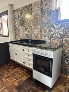 a kitchen with a stove and a wall with tiles at Frank Haus Hospedaria in Treze Tílias