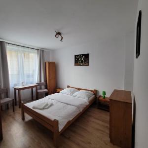 a bedroom with a bed and a table and a window at Willa Roztocze in Zwierzyniec