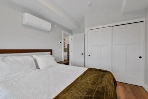 a white bedroom with a large bed and a closet at Harrison Hot Springs Lakeside in Harrison Hot Springs