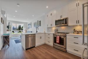 a kitchen with white cabinets and stainless steel appliances at Harrison Hot Springs Lakeside in Harrison Hot Springs