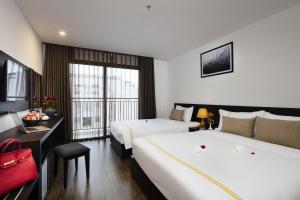 a hotel room with two beds and a desk at Meriton Hotel Nha Trang in Nha Trang