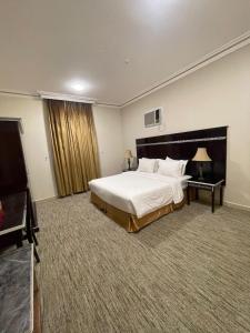 a large hotel room with a bed and a television at Lamasat Al Ajnaha Serviced Apartments in Abha