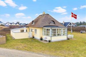 a yellow house with a thatch roof with a flag at 1154-Ringkobing-Nordsovej-50 in Søndervig