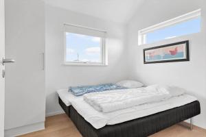 a bed in a white room with a window at 1130-Ringkobing-Sletten-18 in Ringkøbing