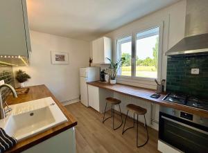 a kitchen with a sink and a counter with stools at Escapade aux portes de Bordeaux, confort et nature in Villenave-dʼOrnon +9 photos