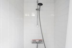 una doccia con un tubo flessibile attaccato a una parete piastrellata bianca di 1083-Ringkobing-Spaettedalen-6 a Nørby Altre 21 foto