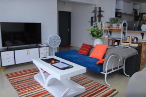 un soggiorno con un divano blu e una TV di The Coffee Residences- 3 Bedroom Apartments-4km to JKIA, 7km to CBD a Nairobi
