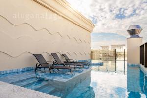 a group of chairs sitting on top of a swimming pool at Aconchego e Lazer no Coração de Itapema in Meia Praia