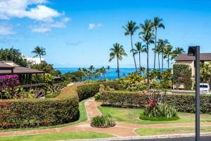 a garden with palm trees and the ocean in the background at WAILEA ELUA, #2107 condo in Wailea