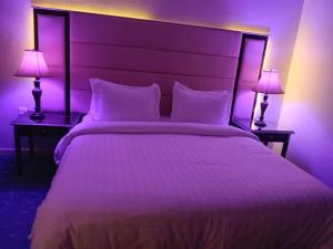 a bedroom with a large white bed with two lamps at Lamasat Al Ajnaha Serviced Apartments in Abha +7 photos