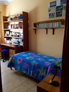 1 dormitorio con cama, escritorio y libros en Pozzetto & Poetto, en Cagliari