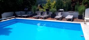 a swimming pool with chairs and a table at Villa-Stern in Keutschach am See
