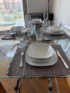 a glass table with white plates and glasses on it at 2 Bed Apt in Ocean Village with Pools Jacuzzi Rock Views in Gibraltar