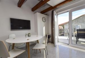 een witte eetkamer met een tafel en een tv bij Mary Rose in Vodice