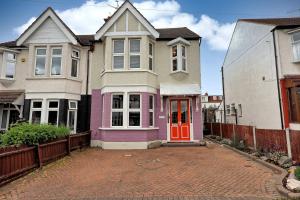 a house with a red door on a brick driveway at Beautiful 5 bed house, relaxing garden and driveway parking 10 min to the beach in Southend-on-Sea