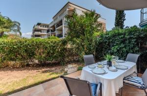 un tavolo bianco con sedie su un patio con un edificio di Saint Raphael appartement 4 étoiles neuf en rez de jardin privatif a Saint-Raphaël