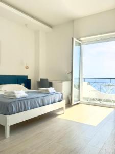 a white bedroom with a bed and a large window at Finestra sul mare Diamante in Diamante +25 photos