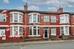 a red brick house with flags in front of it at 4BR Home in Great Location close to Transport in Liverpool