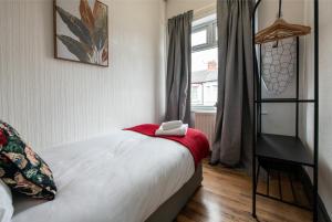 a bedroom with a bed with a red blanket and a shelf at 4BR Home in Great Location close to Transport in Liverpool