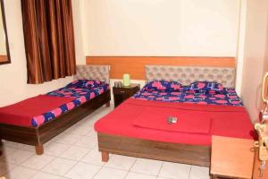 two beds in a bedroom with red and blue sheets at SAIRATNA HOTEL only 1 minute distance from sai temple in Shirdi