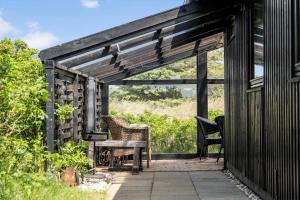 een afgeschermde veranda met een tafel en stoelen bij 235-Ringkobing-Vestklitvej-11 in Klegod