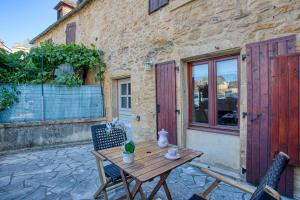 Maison 3 pièces , terrasse LA BOUQUERIE في سارلا لا كانيدا: طاولة وكراسي خشبية أمام المبنى