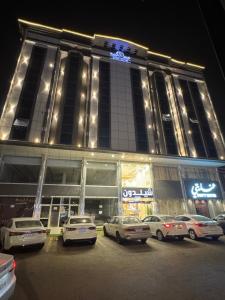 a large building with cars parked in a parking lot at شقق شيل دون للشقق المخدومة in Muhayil