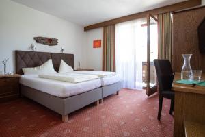 a bedroom with a bed and a desk and a window at Ferienhotel Bergland in Arzl im Pitztal