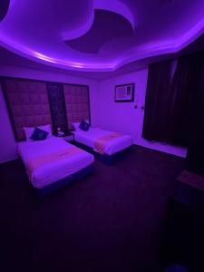 two beds in a room with purple lights at شقق شيل دون للشقق المخدومة in Muhayil