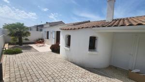 ein weißes Haus mit einer Terrasse davor in der Unterkunft Maison Quartier du Phare in La Tranche-sur-Mer + 2 Fotos